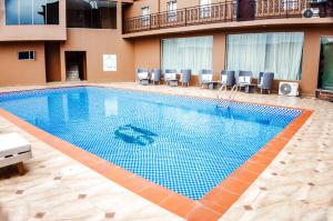 a large swimming pool in a hotel with chairs at Swisse International Rancho Valeria Hotel & Suites in Warri