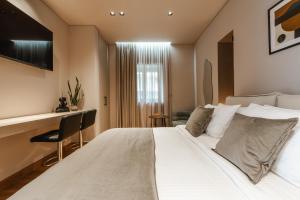 a bedroom with a large white bed and a window at Grava Aurum - City Suites in Igoumenitsa