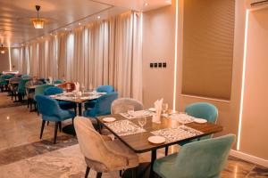 a dining room with tables and blue chairs at Swisse International Rancho Valeria Hotel & Suites in Warri