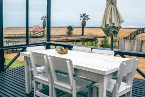 a white table and chairs and an umbrella and the beach at Lalandi 14 - Beachfront Self-Catering- Langstrand Walvis Bay in Langstrand