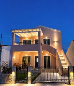 a white house with a fence in front of it at Olea Verde Loft Apartment in Lefkimmi
