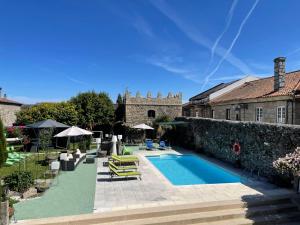 a swimming pool in a yard with chairs and umbrellas at Casa do Torreão in Trancoso