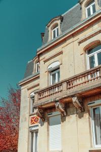 a stone building with a balcony on the side of it at La Source de la Scance in Verdun-sur-Meuse