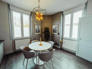 a dining room with a table and chairs and windows at La Source de la Scance in Verdun-sur-Meuse