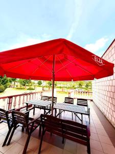 a red umbrella on a patio with tables and benches at Zajazd-Restauracja ELZA in Kutno