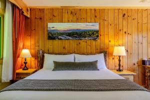 a bedroom with a bed with wooden walls and two lamps at Adirondack Spruce Lodge in Wilmington
