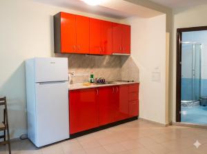 a kitchen with red cabinets and a white refrigerator at Апартаменти Спас 2 in Sinemorets