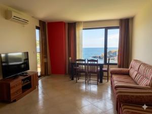 a living room with a couch and a television and a table at Апартаменти Спас 2 in Sinemorets