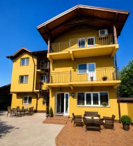 a yellow building with tables and chairs in front of it at Vila Dana in Costinesti