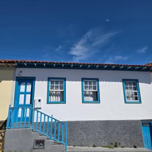 a white house with blue windows and a blue railing at Casa Centro Exclusiva Diamantina in Diamantina
