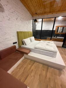 a large bed in a room with a brick wall at ART Sattal in Bhīm Tāl