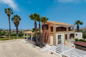 a house with palm trees in front of it at Villa Cielo in Paceco