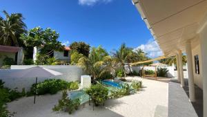 a swimming pool with an umbrella next to a house at EcoWave Retreat- Muli in Muli