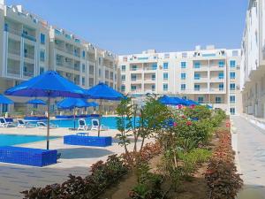a hotel with blue umbrellas and a swimming pool at Hurghada HuB in Hurghada