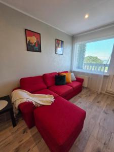 a living room with a red couch and a window at Lake Breeze Stay in Liepāja