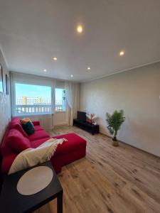 a living room with a red couch and a large window at Lake Breeze Stay in Liepāja