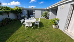 a patio with a table and chairs on the grass at Pet-Friendly, 3-Bed, 2-Bath in Knysna Central in Knysna