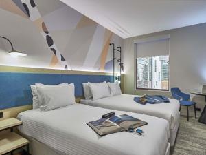 a hotel room with two beds with a book on them at ibis Perth in Perth +158 photos