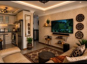 a living room with a couch and a tv on a wall at Eluthando Guesthouse in St Lucia