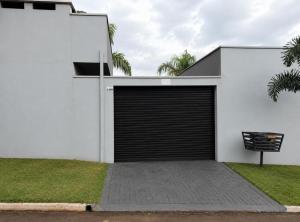 a white house with a black garage door at Pousada Rancho do Sossego in Céu Azul +1 photo