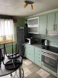 a kitchen with green cabinets and black appliances at Mugavustega avar perekorter 3toaline in Võru