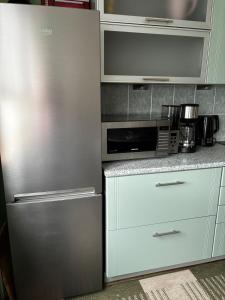 a kitchen with a stainless steel refrigerator and a microwave at Mugavustega avar perekorter 3toaline in Võru +3 photos