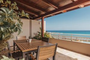 a wooden table and chairs on a balcony with the beach at Level 3 Sea View Studio in Planos
