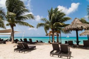 a beach with chairs and palm trees and the ocean at Cadaques Caribe Bayahibe Palmera in Bayahibe