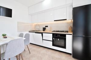 a kitchen with white cabinets and a black refrigerator at Apartments Sonja in Tučepi