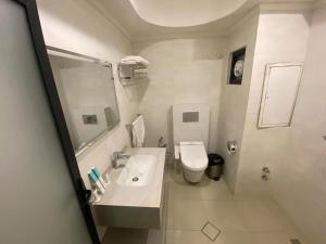 a white bathroom with a sink and a toilet at فندق قصر السدير in Baghdād