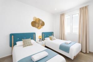 two beds in a room with white and blue at Villa Maria 7 in Puerto Calero +10 photos