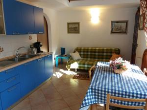 a kitchen with blue cabinets and a table and a couch at Appartamento in VILLA spazio esterno e posto auto in Rio nellʼElba