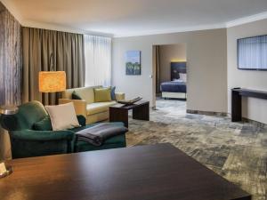 a living room with a couch and chairs and a bed at Mercure Hotel Hagen in Hagen