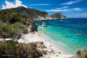 a beach with people on the sand and the water at Appartamento in VILLA spazio esterno e posto auto in Rio nellʼElba