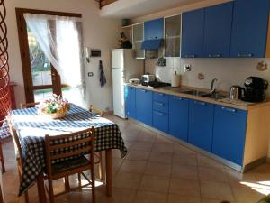 a kitchen with blue cabinets and a table with a table cloth at Appartamento in VILLA spazio esterno e posto auto in Rio nellʼElba +22 photos