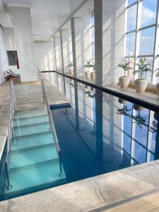 a swimming pool with blue water in a building at The Cittyplex Osasco - new flat in Osasco