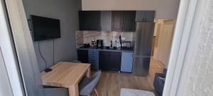 a kitchen with black cabinets and a wooden table at Tri Kule Apartman in Bar