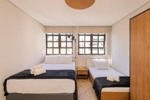 two beds in a room with two windows at One House by Anora Spaces in São Paulo