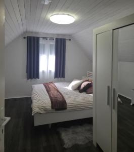 a bedroom with a bed with blue curtains and a window at Kuća za odmor Štiba in Vinkovci +24 photos