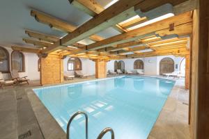 a large swimming pool in a building with a wooden ceiling at Hotel Rosatsch Residence in Pontresina +90 photos