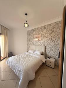 a bedroom with a bed and a wall with floral wallpaper at Asilah in Asilah