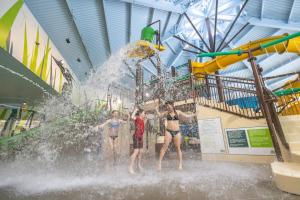 three people standing in the water at a water park at Country house with SPA, small beach, pool in Mont-Tremblant