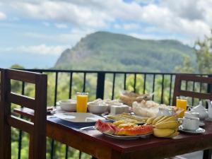 a breakfast table with food on a balcony with a view at Senu Ceylon Ella in Ella