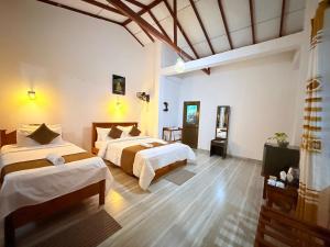 a hotel room with two beds and a television at Senu Ceylon Ella in Ella