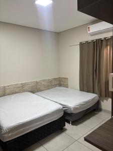 two beds in a room with white walls at Recanto R2V in Chapada dos Guimarães +9 photos