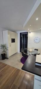 a living room with a dining table and a clock on the wall at Apartman Jo Ma MA in Solin