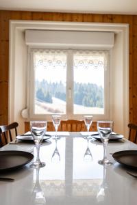 a table with glasses and plates and a window at Gites des Gentianes in Morbier