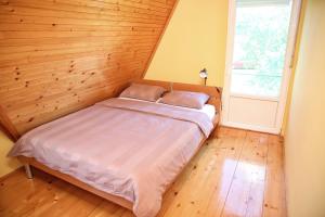a bed in a room with a wooden wall at Vila Zeleno borje in Žabljak
