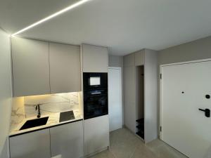 a kitchen with white cabinets and a sink at Esch City Studio in Esch-sur-Alzette