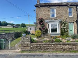 a brick house with a green door and flowers at Dale Grange in Askrigg